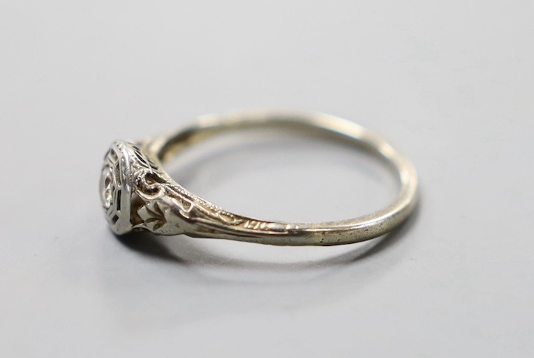 A white metal and collet set solitaire diamond ring, size J, gross weight 1.3 grams.